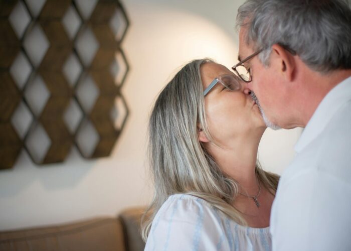 un couple senior échange un baiser tendre dans un salon lumineux, célébrant un amour né grâce à une plateforme de rencontres pour seniors