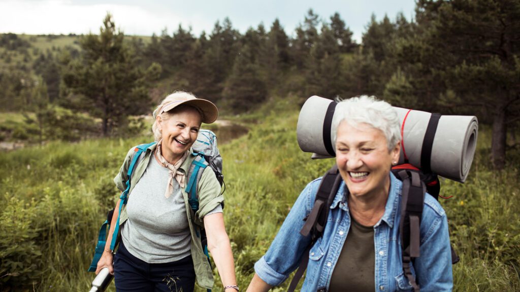 deux femmes seniors marchant ensemble lors d'une randonnée, illustrant la confiance en soi retrouvée après un divorce, en s'engageant dans des activités qui favorisent le bien-être et l'épanouissement personnel