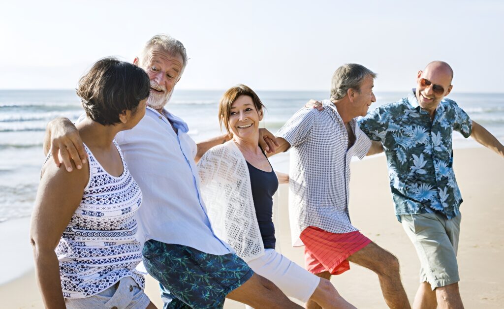 groupe de seniors heureux et détendus profitant de leur temps à la plage, montrant que les rencontres en ligne peuvent mener à des activités conviviales et enrichissantes entre célibataires seniors