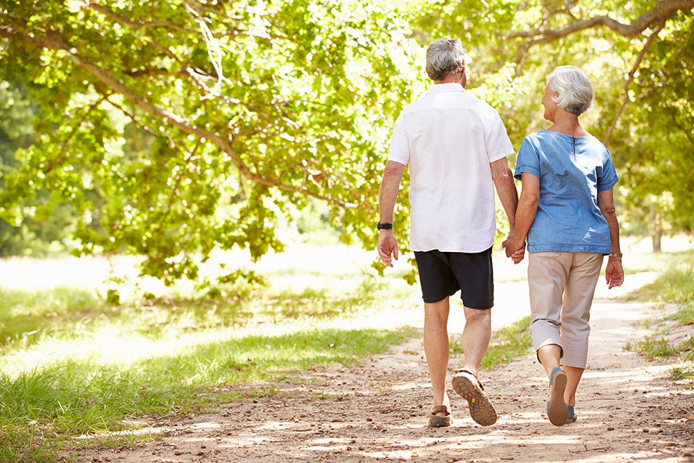 couple senior se promenant ensemble dans la nature, symbolisant l'importance de l'activité physique et des moments partagés pour rester actif et épanoui après 50 ans