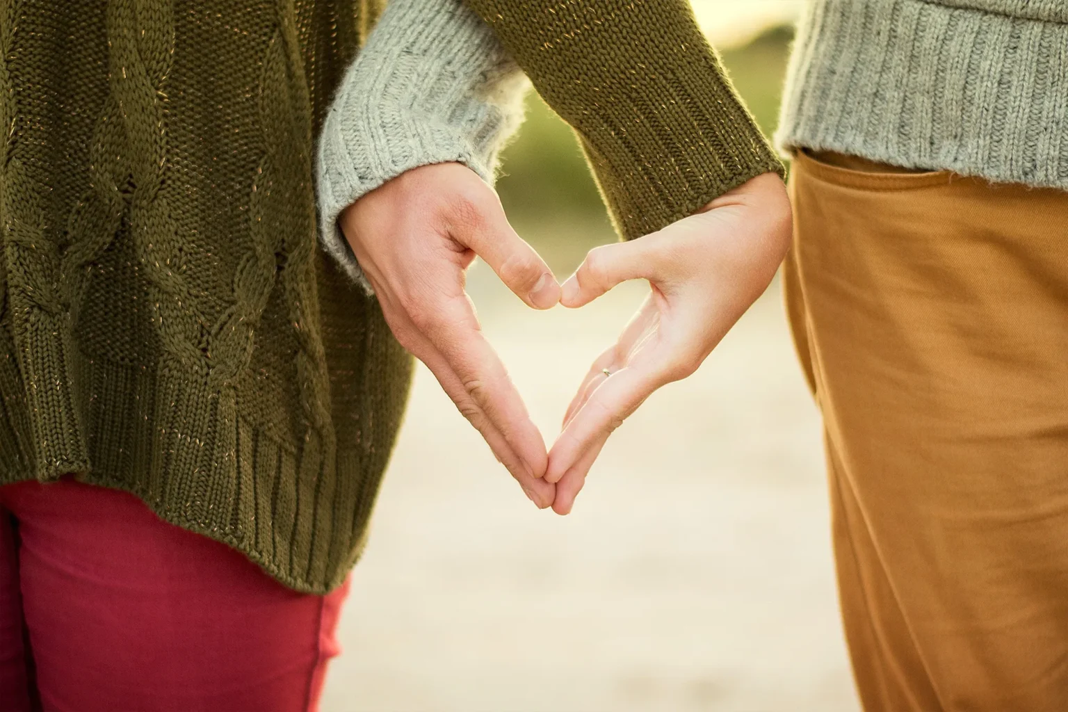 couple senior souriant marchant main dans la main sur une plage au coucher du soleil, symbole de l'amour après 50 ans