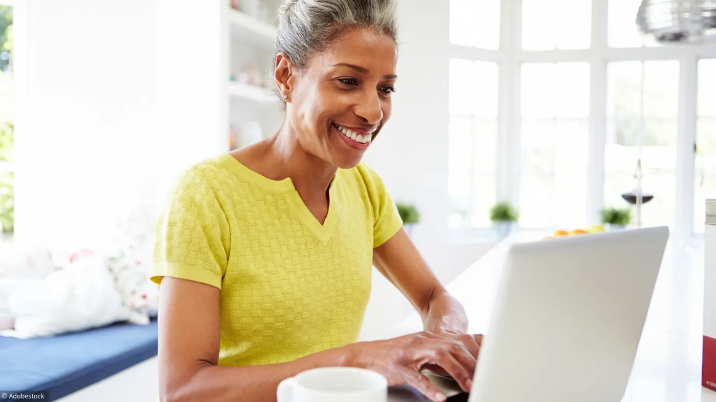 femme senior souriante devant son ordinateur, illustrant l’utilisation des sites de rencontres sécurisés pour seniors, offrant une opportunité de rencontre et de connexion en ligne