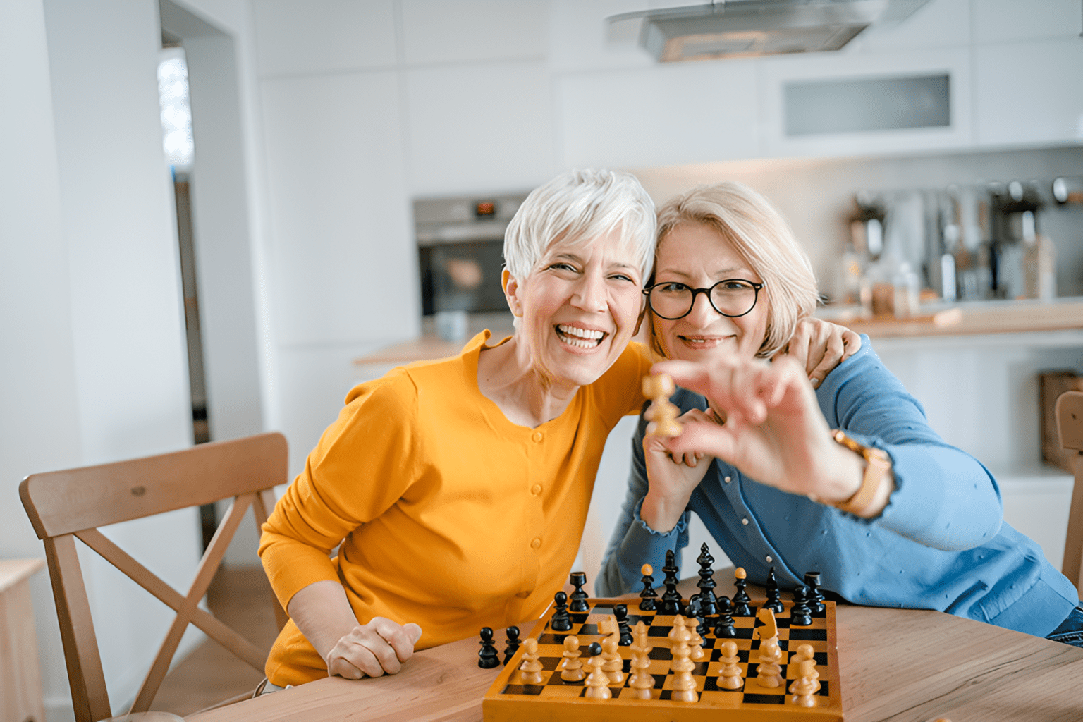 deux femmes seniors jouant aux échecs, illustrant l'engagement intellectuel et les rencontres amicales autour de jeux de société, favorisant les liens sociaux et la stimulation mentale