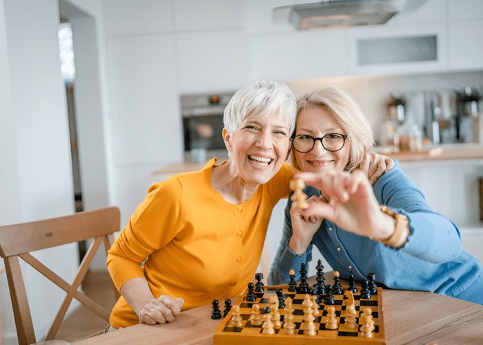 deux femmes seniors jouant aux échecs, illustrant l'engagement intellectuel et les rencontres amicales autour de jeux de société, favorisant les liens sociaux et la stimulation mentale